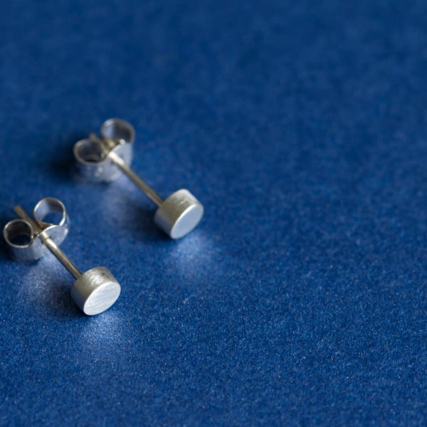 Silver cylindrical ear studs with a brush matte texture