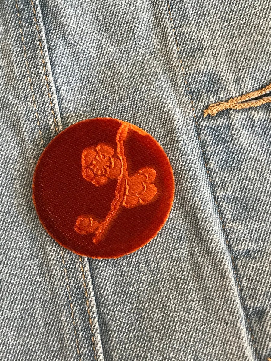 Orange floral brooch with embossed velvet design and pin fastening to back.