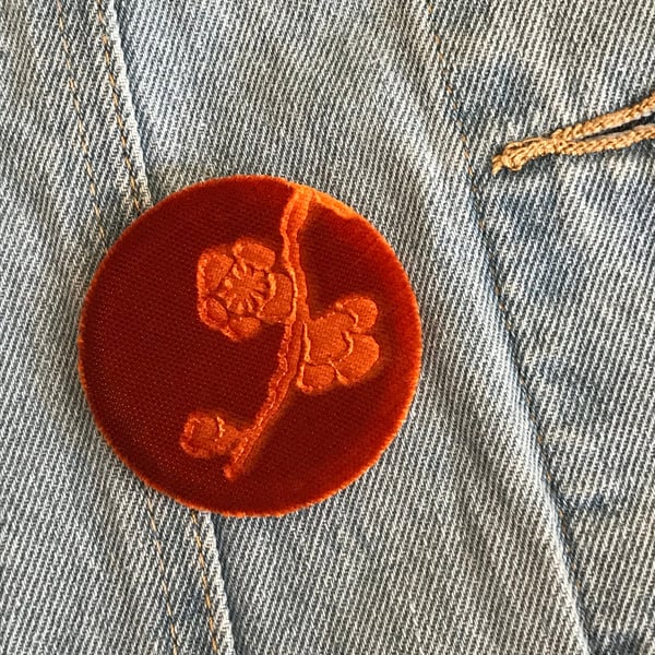 Orange floral brooch with embossed velvet design and pin fastening to back.