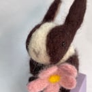 Handcrafted needle felted rabbit holding a flower on a wooden box