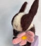 Handcrafted needle felted rabbit holding a flower on a wooden box