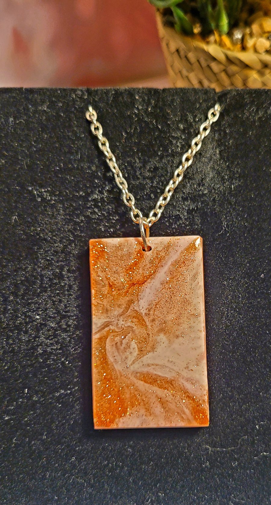 a resin pendant in golds with a silver style chain