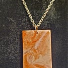 a resin pendant in golds with a silver style chain