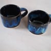 Set of two pottery mugs finished in blue and black glaze combination.