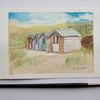 Small watercolour painting of beach huts on a sandy beach 