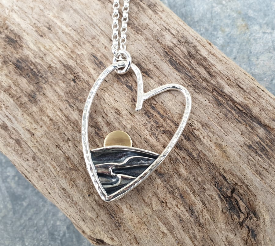 Silver heart shaped sun rising over the sea pendant