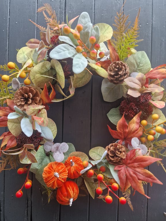 Autumn wreath with plush orange pumpkins, pinecones, berries and mixed foliage. 