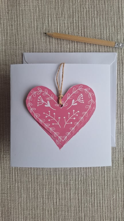 Linoprinted greetings card featuring heart and attached heart decoration.