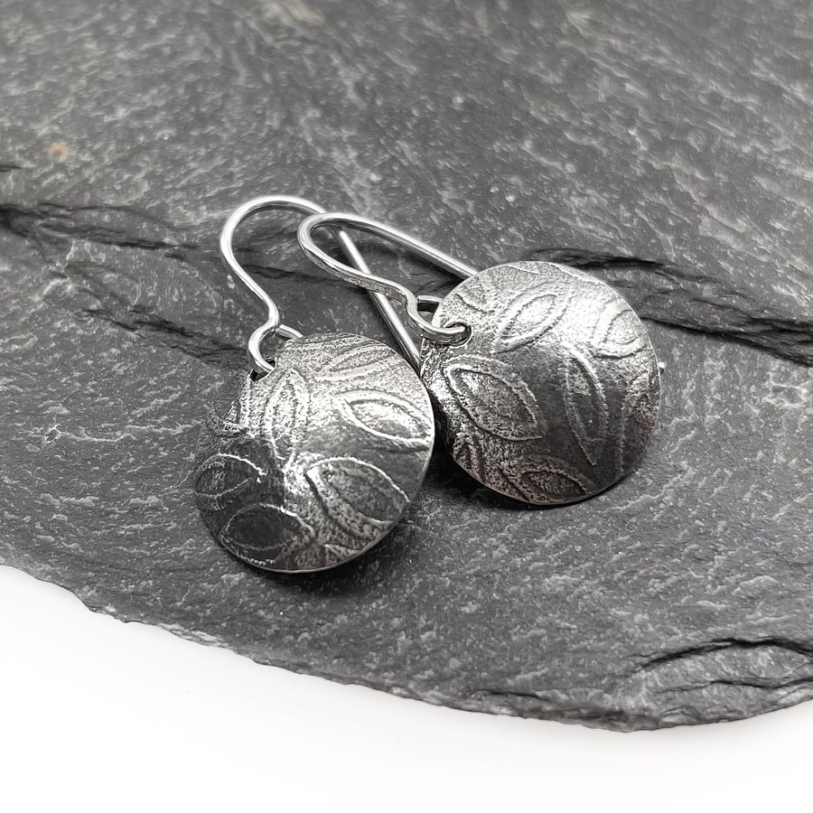 Sterling silver leaf patterned circular earrings.