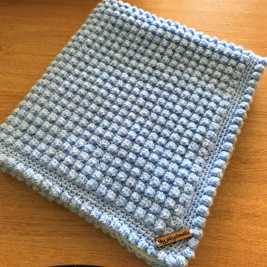 Hand crocheted baby blanket in pale blue with white fleece lining
