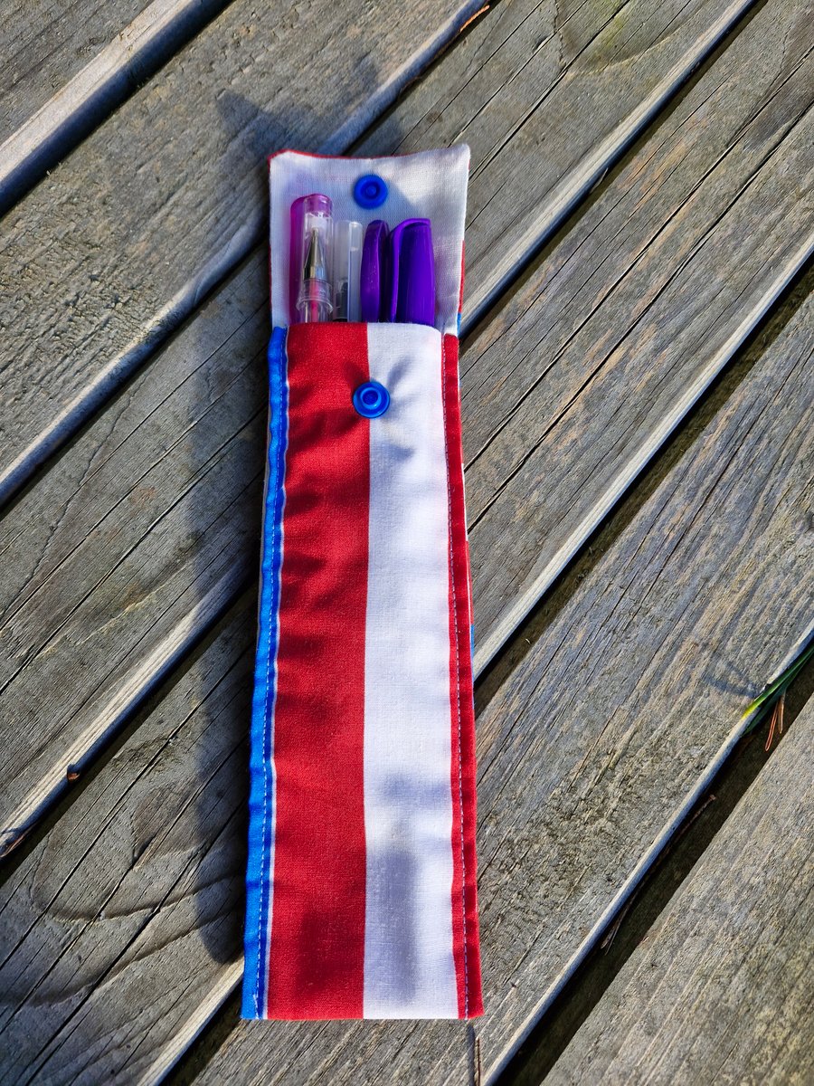 White, red and blue striped pen case with purple pens