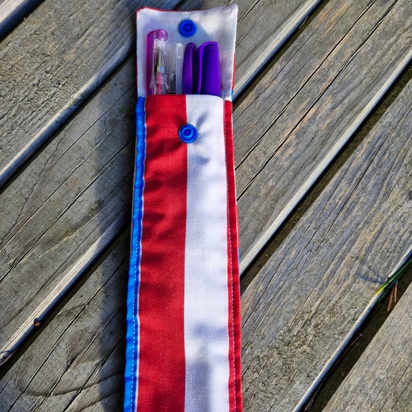 White, red and blue striped pen case with purple pens