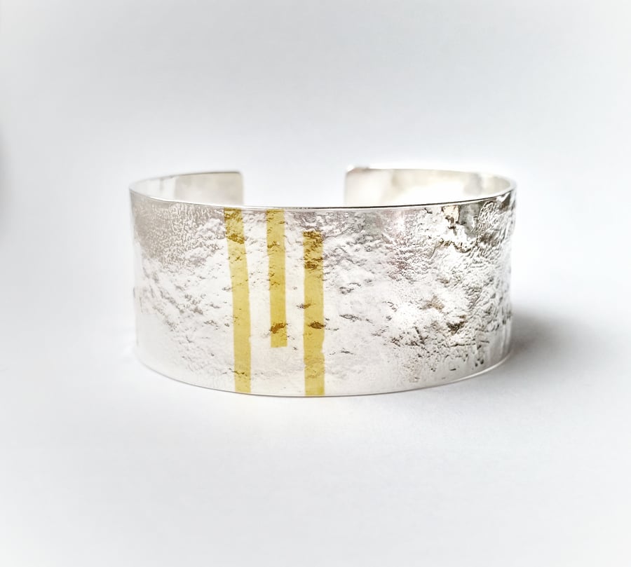 A beautiful solid silver textured cuff bracelet with gold accents