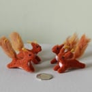 Wee red squirrels leaping -ginger