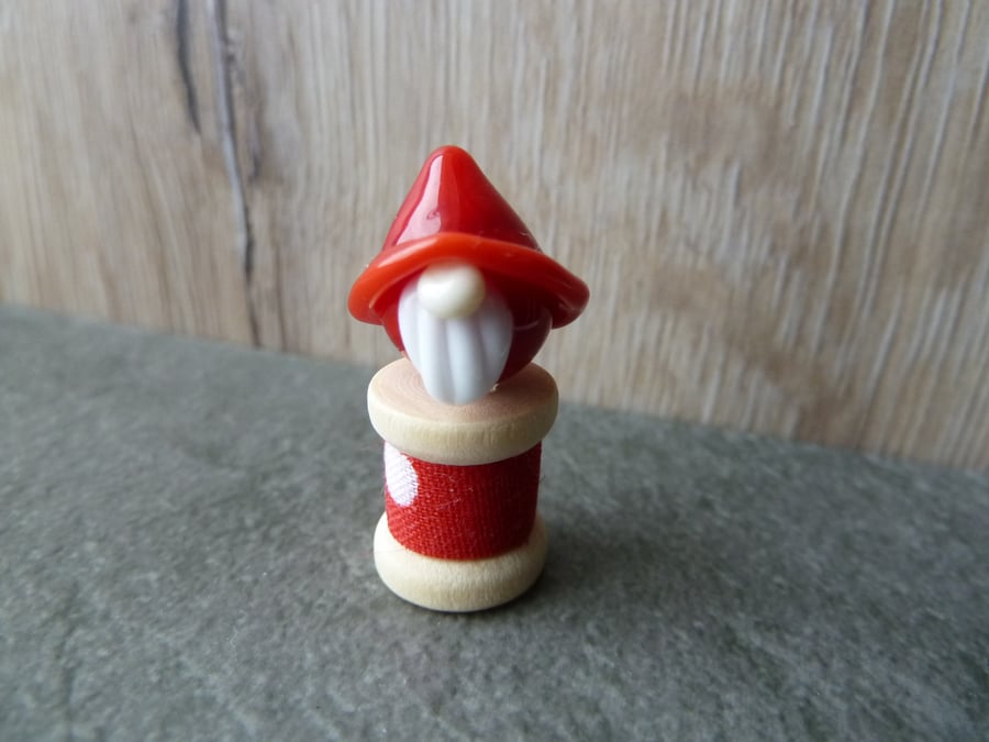 red glass gnome on a wooden spool