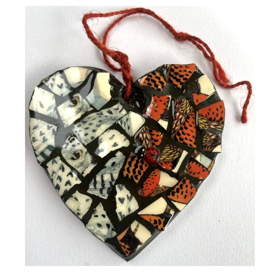 A heart shaped mosaic pendant with a snowy owl and partridge theme. 