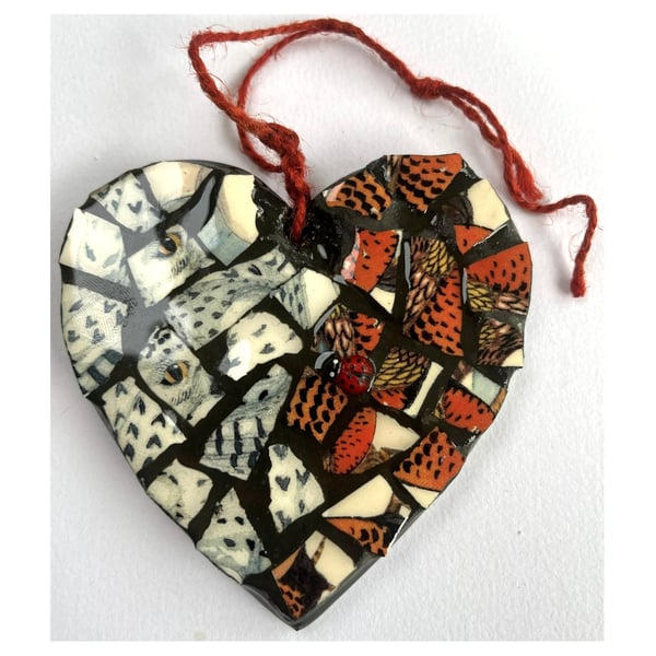 A heart shaped mosaic pendant with a snowy owl and partridge theme. 