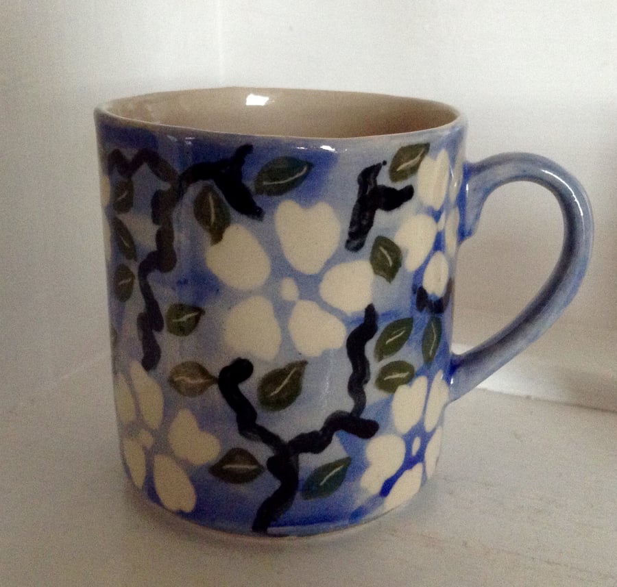 Mugs with floral design in blue, black and green, holding half a pint