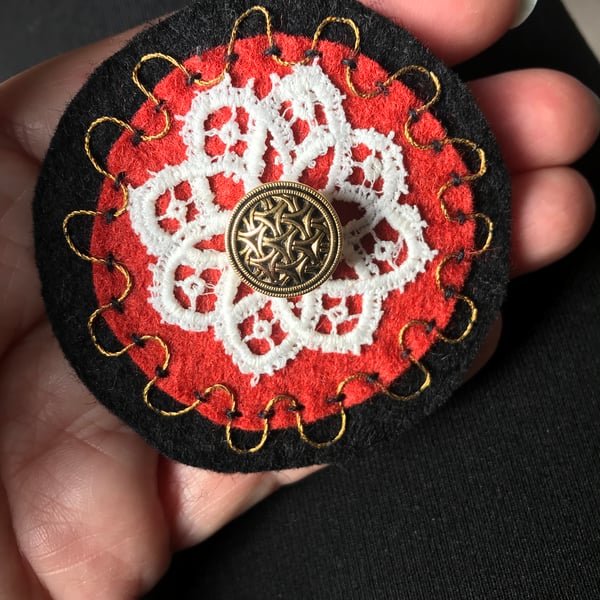 Hand embroidered corsage in black, cinnamon and gold.