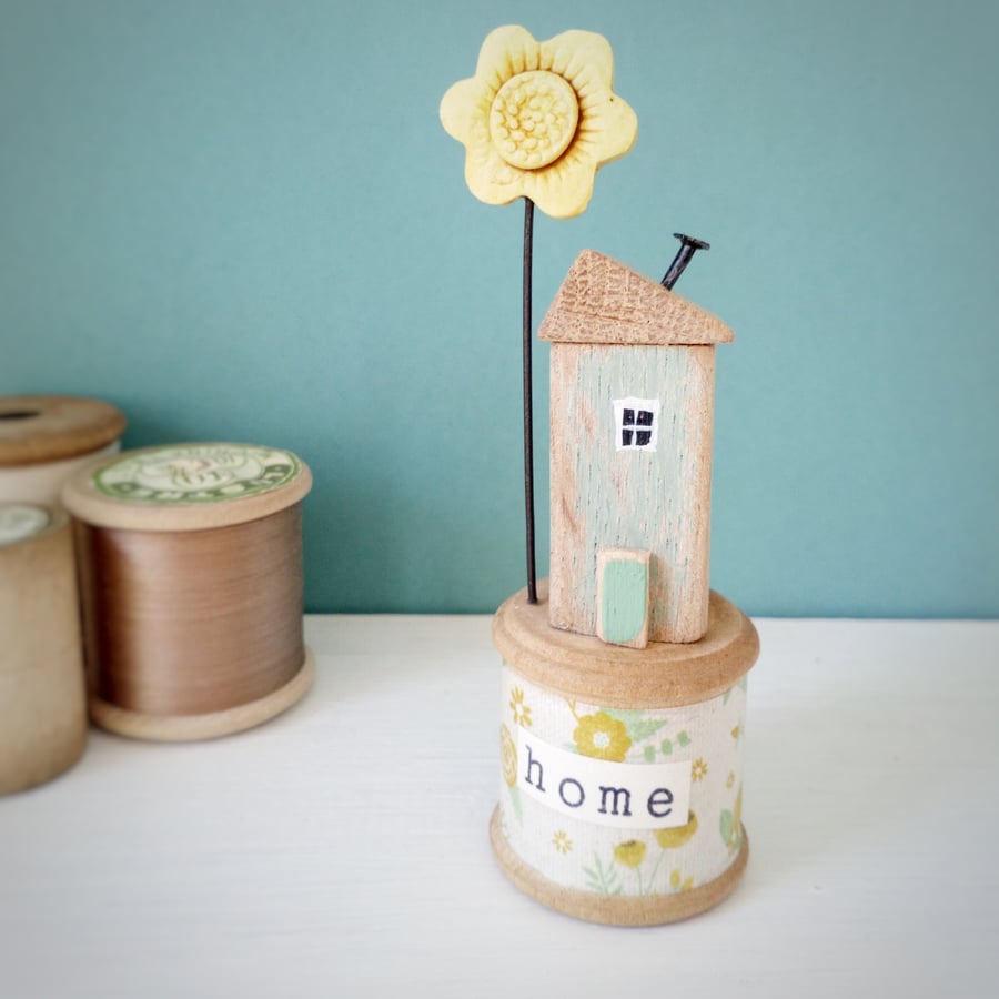 Little oak wood house with clay flower on a vintage bobbin 'Home' 