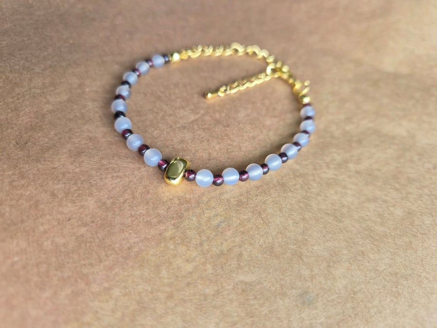 Owl grey and deep red, strength stone, gold bracelet.