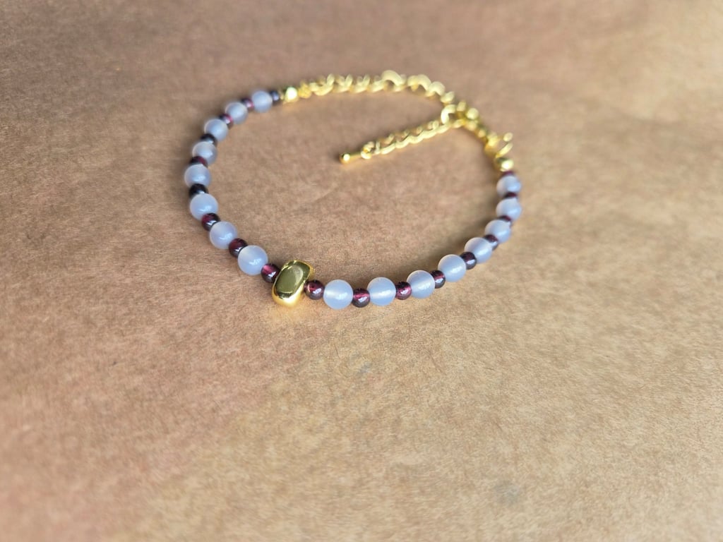 Owl grey and deep red, strength stone, gold bracelet.