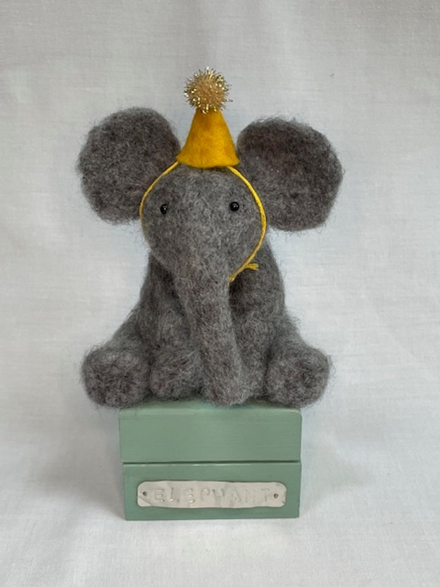 Handcrafted needle felted elephant with removable party hat on a wooden box