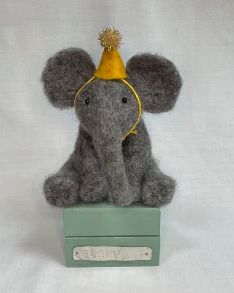 Handcrafted needle felted elephant with removable party hat on a wooden box