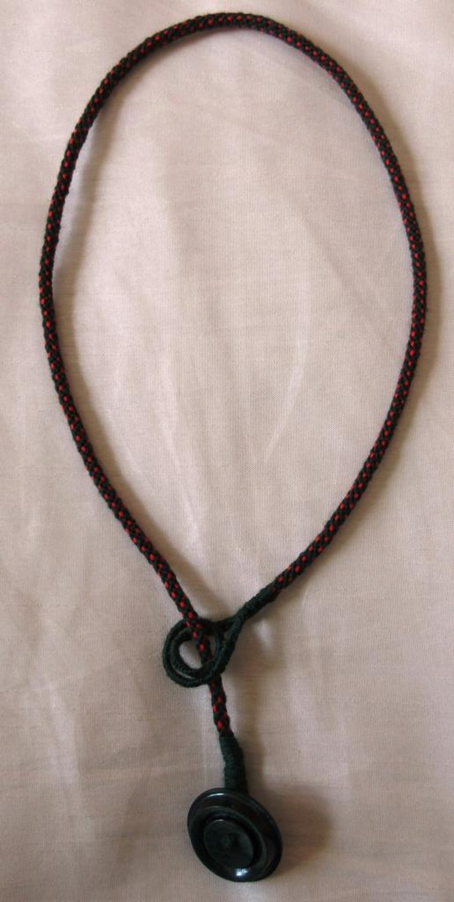 A lariat-style necklace in kumihimo braid with button trim