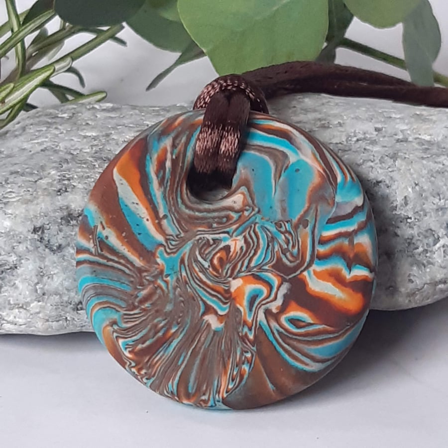 Round polymer clay pendant in a colourful swirl design