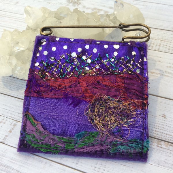 Embroidered up-cycled abstract landscape kilt pin brooch. 