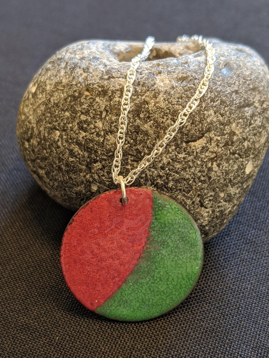 Enamel on copper, green and brown red disc with a silver bail on a silver chain.