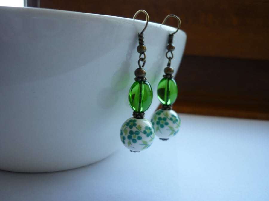 GREEN, WHITE AND ANTIQUE BRONZE PORCELAIN BEAD EARRINGS.