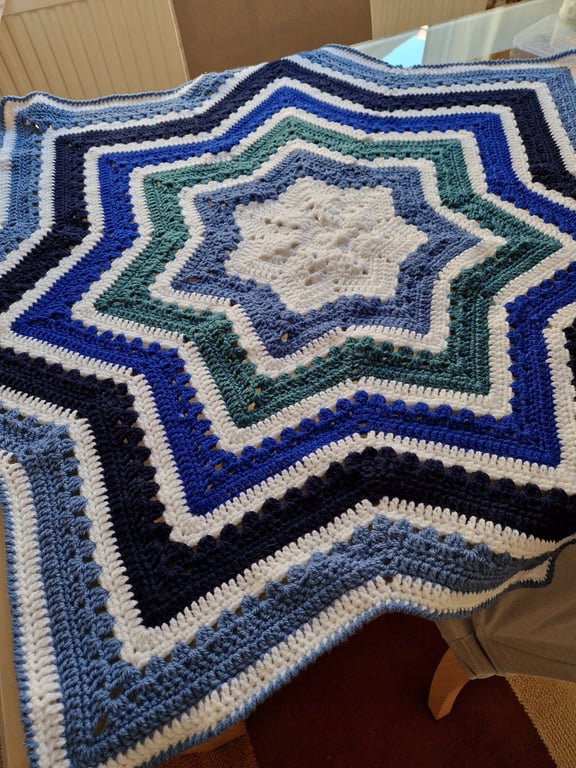Handmade crochet baby blanket star shaped in stripes of white and shades of blue