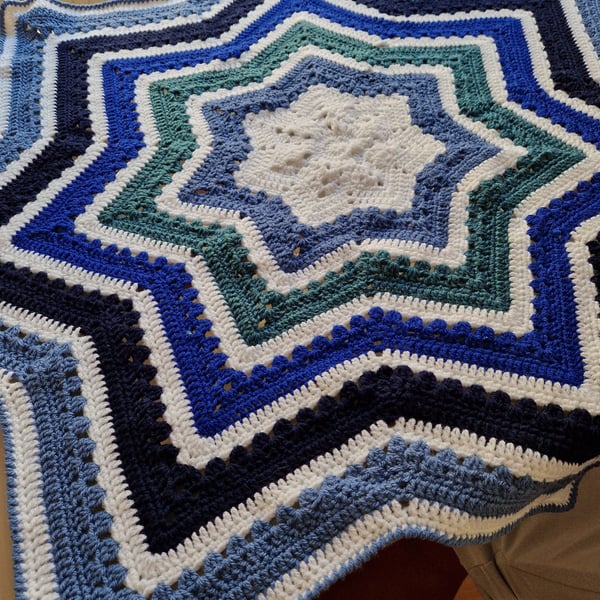 Handmade crochet baby blanket star shaped in stripes of white and shades of blue
