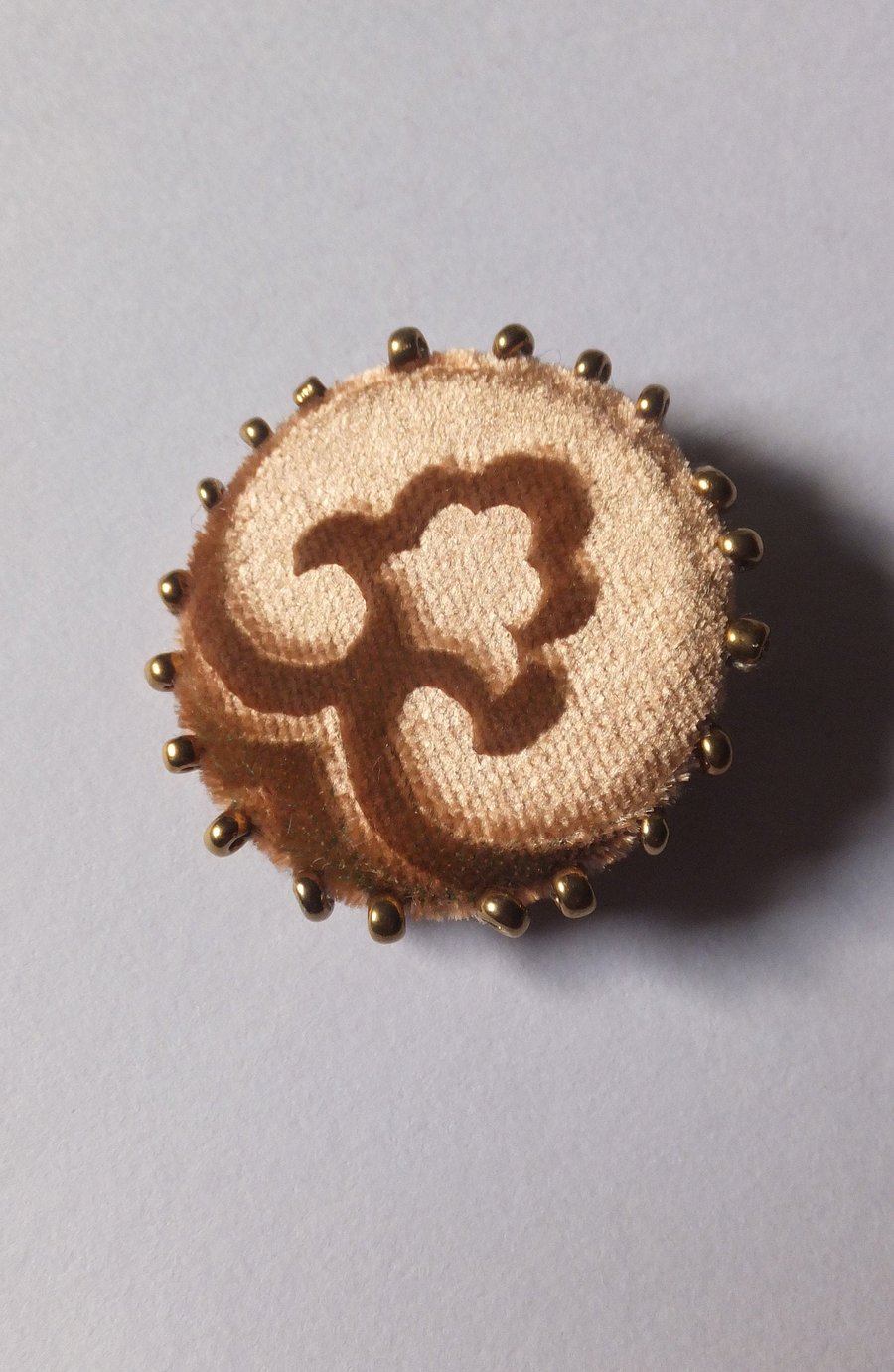 Gold velvet brooch with beaded and embossed design and pin fastening to back.