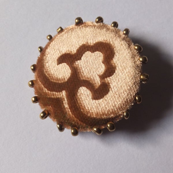 Gold velvet brooch with beaded and embossed design and pin fastening to back.
