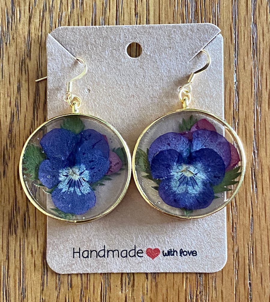 Round Gold-Rimmed Earrings With A Pressed Viola Flower And Leaves In Resin.