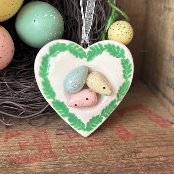 Pottery heart decoration with little eggs in a nest