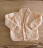 Handmade peach coloured v-necked baby cardigan age 0-3 months.