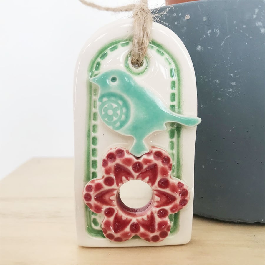 Small decorative pottery gift tag with flower and bird hanging decoration