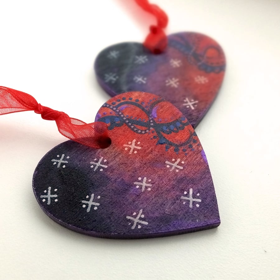 Heart shaped pair of handpainted Christmas decorations with red swirls