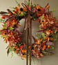 Lush autumn wreath with orange Hydrangea, Orange red berries, maple leaves.