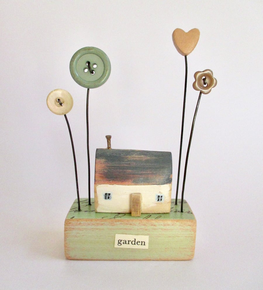 Little wooden painted house with buttons and clay heart garden