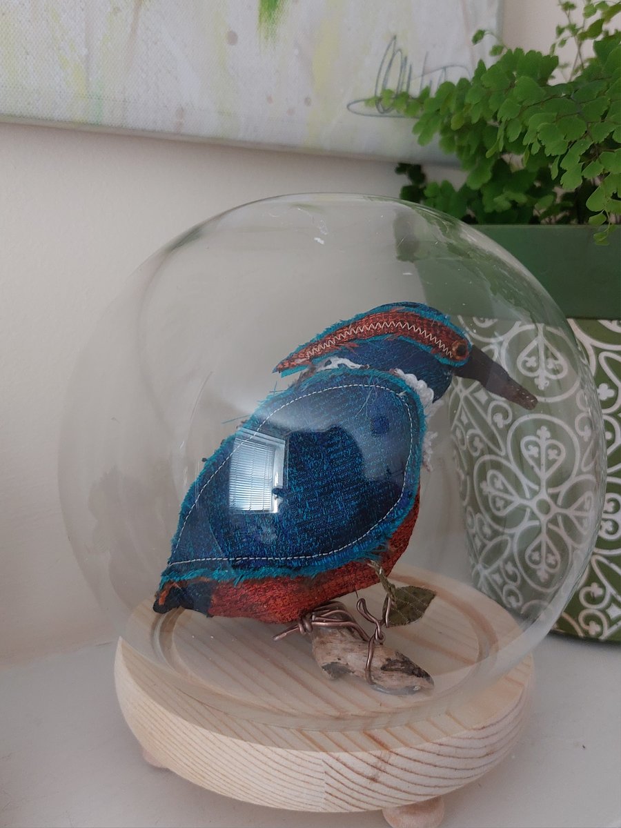 Kingfisher inspired soft sculpture in glass case.
