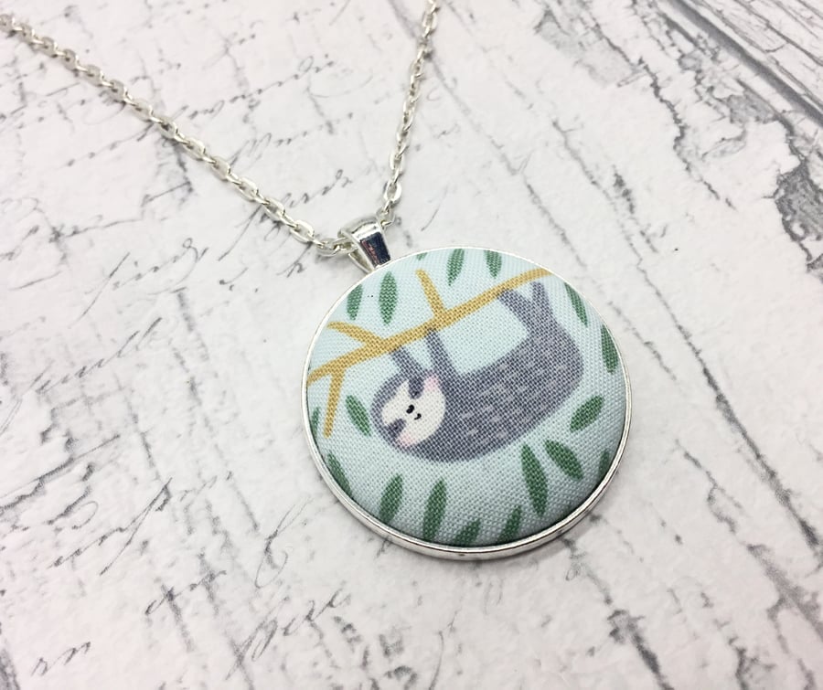 Sloth hanging or waving in a tree fabric button pendant