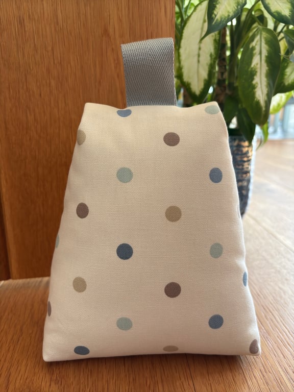 Cotton fabric doorstop in cream with pastel polka dots, filled with pebbles.