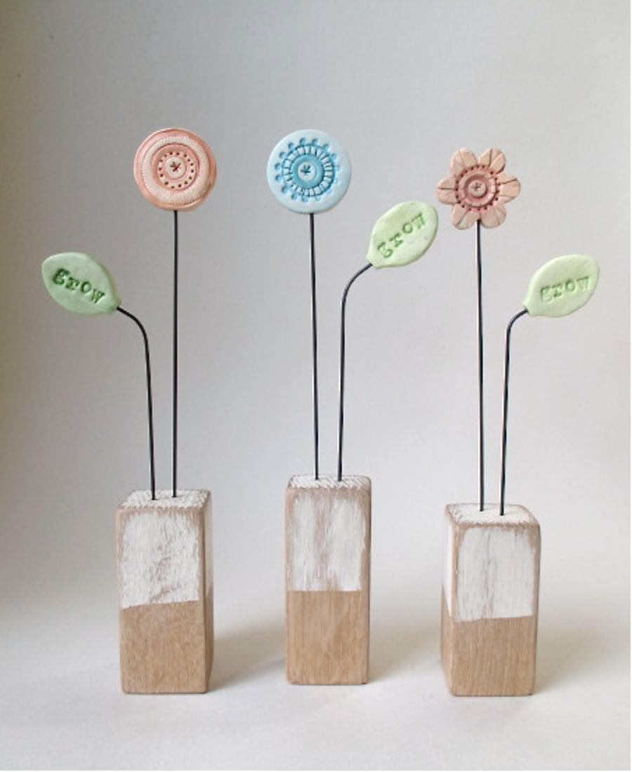 Clay Painted Flower and Leaf imprinted with the word 'grow' on Wooden Block