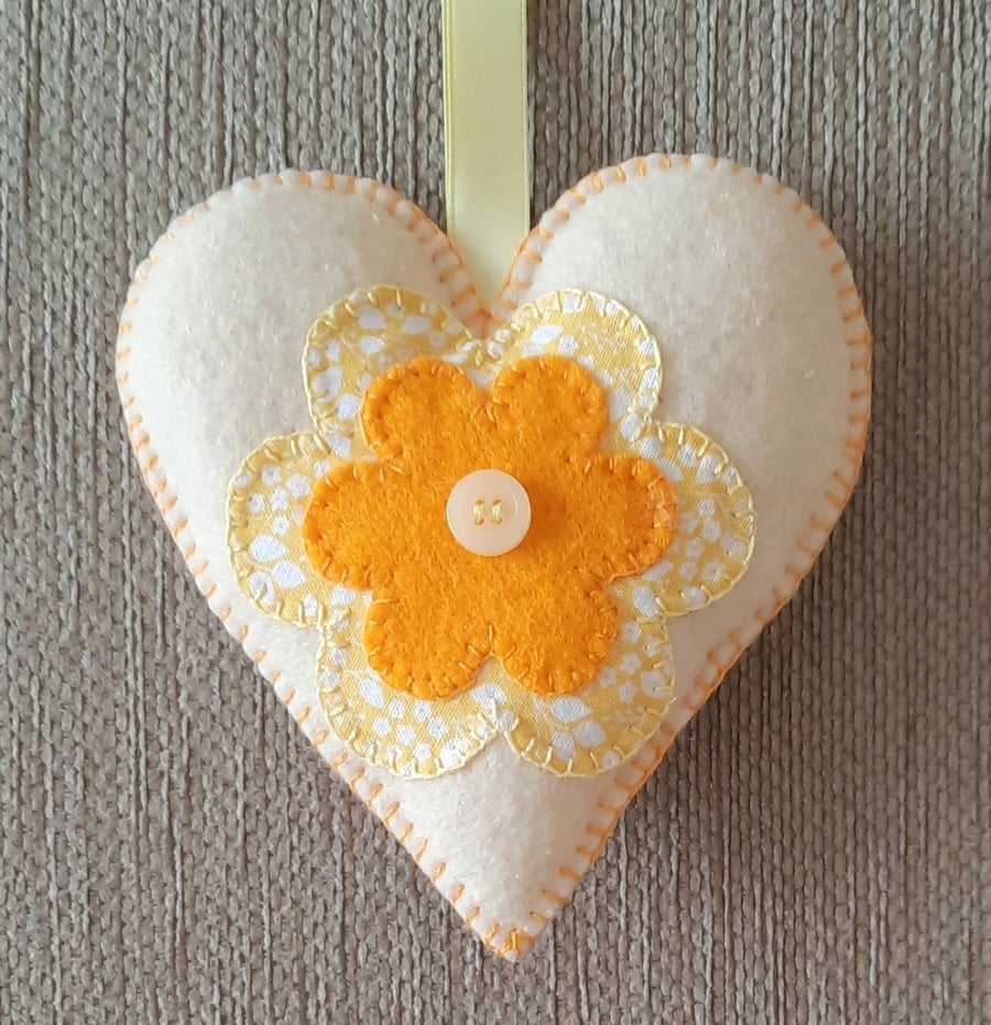 A handmade cream and orange  floral felt heart hanging decoration 