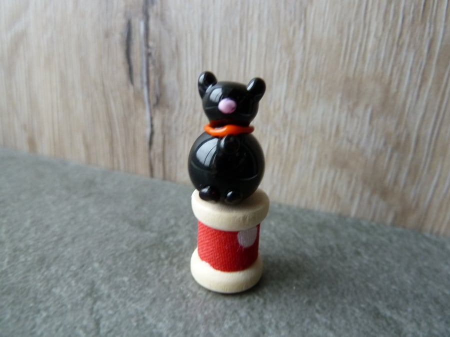glass cat on wooden bobbin 